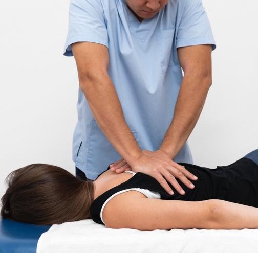 Chiropractor performing spinal adjustment on patient during addiction recovery treatment, demonstrating holistic approach to substance use disorder management